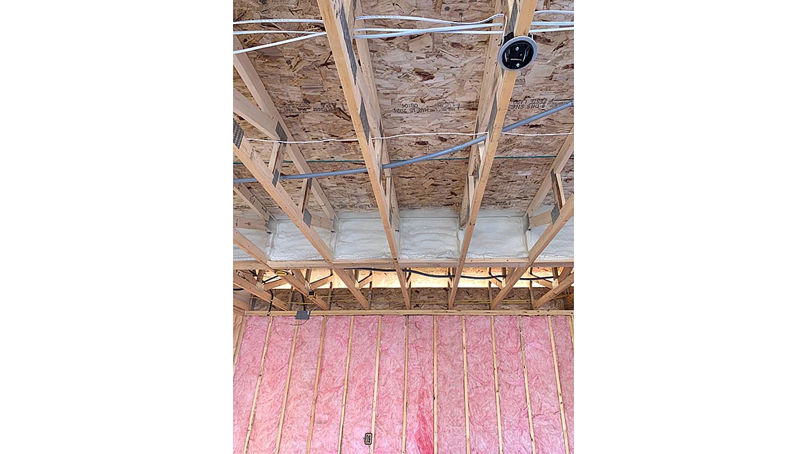 A wall full of fiberglass insulation and wood framing
