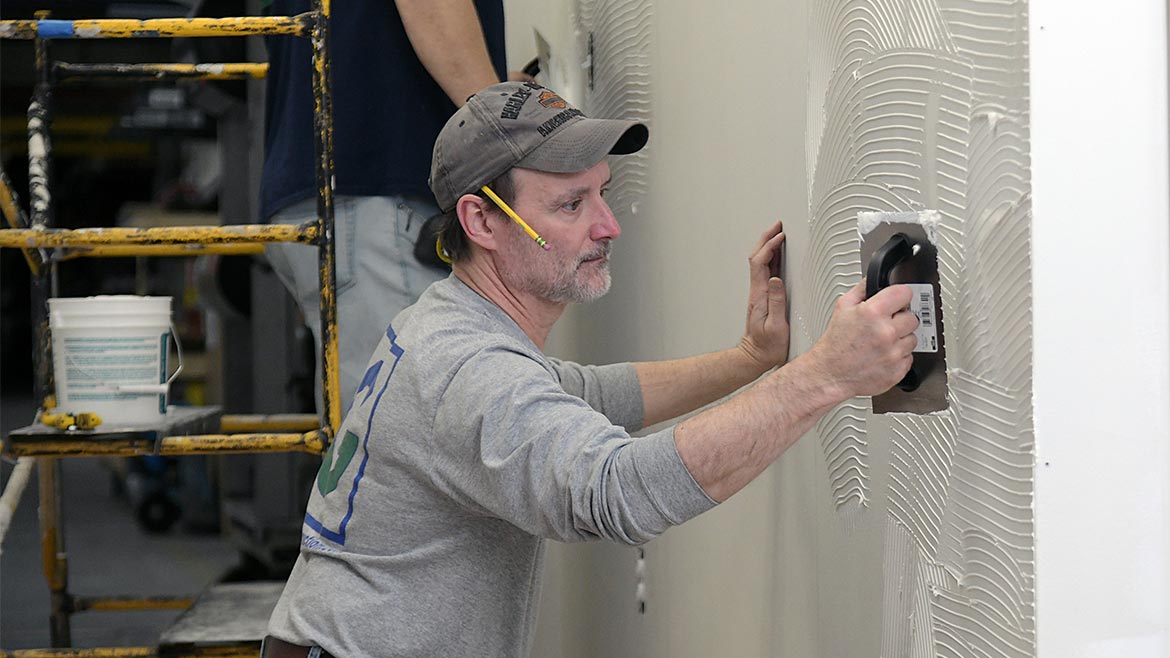 Using a trowel to apply Rigid Sheet Wall Protection