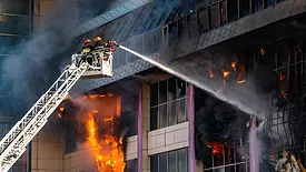 A firefighter on a ladder with a hose