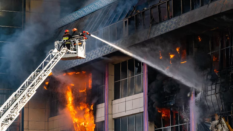 A firefighter on a ladder with a hose