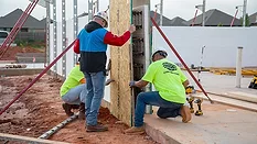 3 workers placing a wall at a construction site