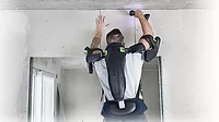 A man wearing an exoskeleton assembly while drilling